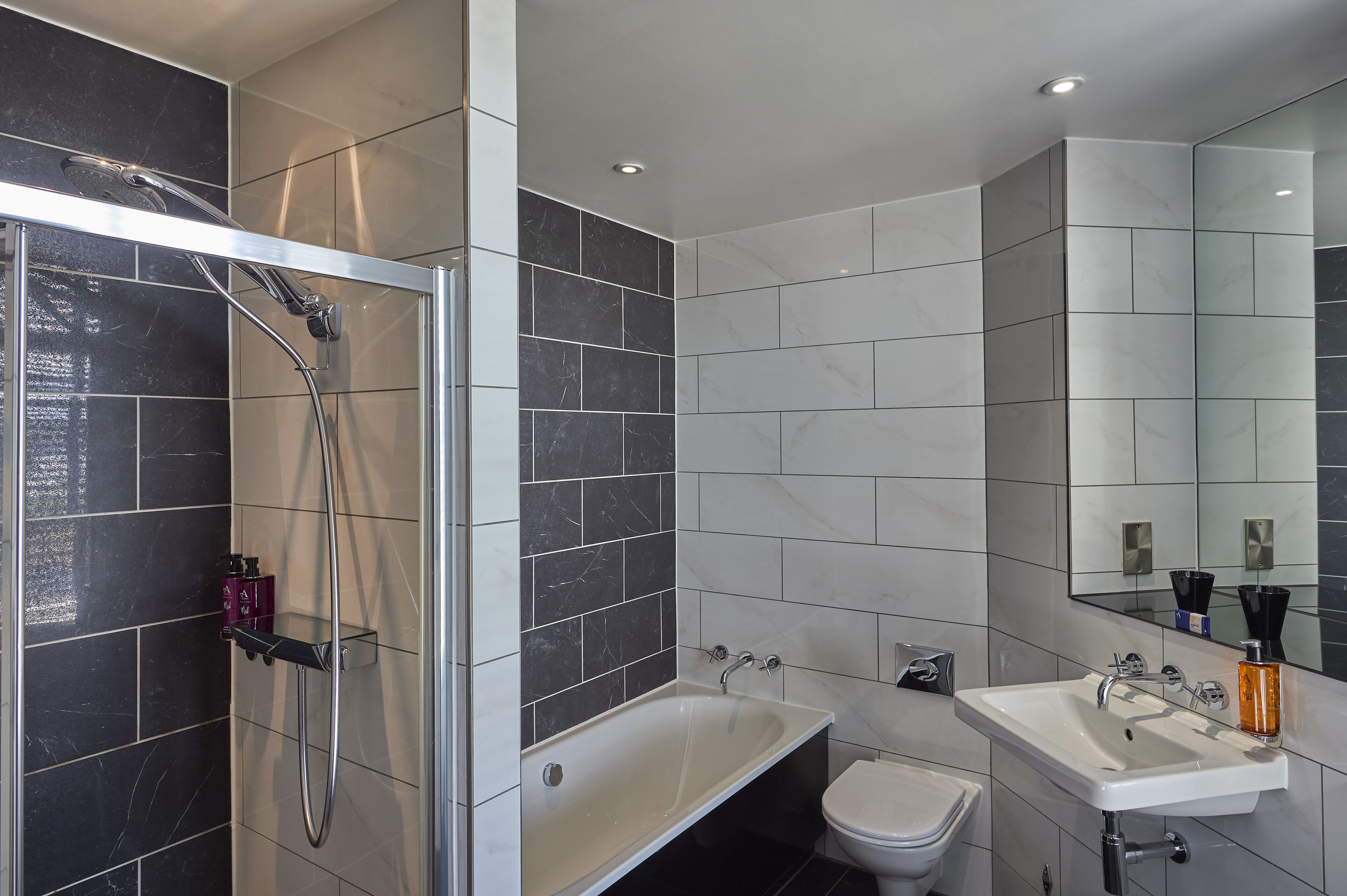 Een moderne badkamer met een douchecabine, een vrijstaand bad en een wastafel met spiegel.