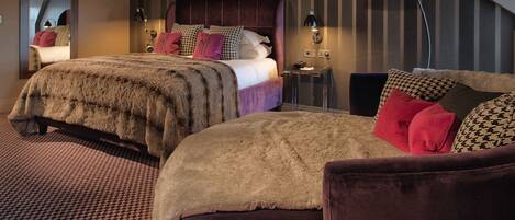 A modern bedroom with a large bed, a smaller bed, a desk, and a chair.