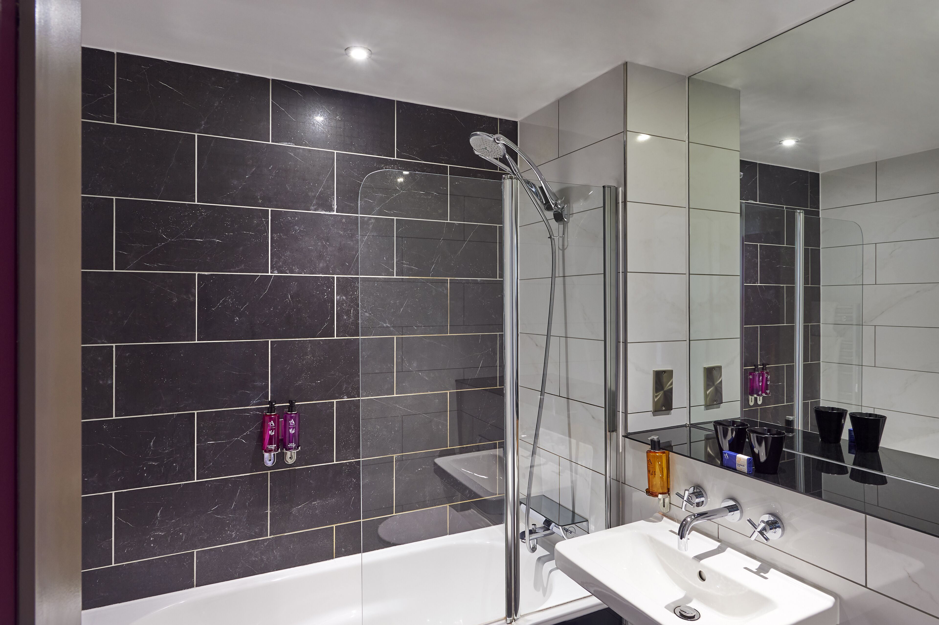 A modern bathroom with a glass-enclosed shower, a white sink, and a large mirror.