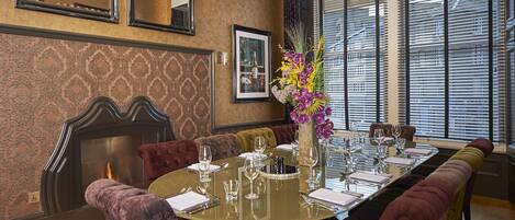 A dining area with a round table set for six, surrounded by plush red and purple upholstered chairs.