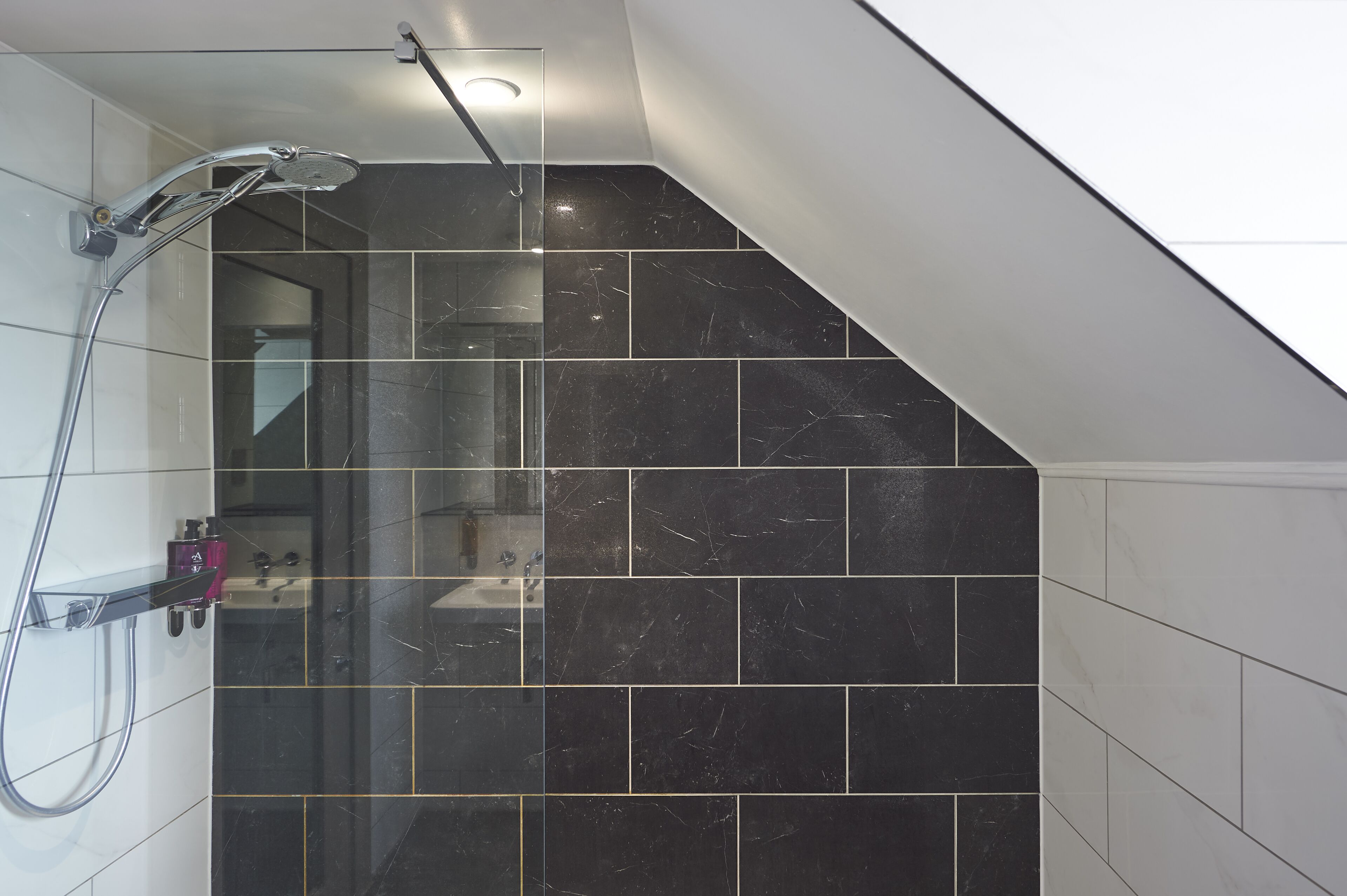 A modern shower area with a glass door, a handheld showerhead, and a control panel.