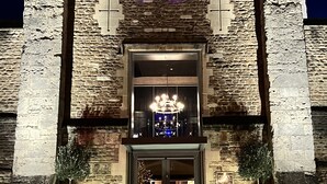 A building with a stone facade, a neon sign reading "Malmaison," and a large chandelier above the entrance. - Malmaison Oxford (Oxford)