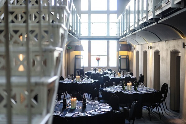 A dining area with multiple tables set for a meal, featuring candles and glassware. - Malmaison Oxford (Oxford)