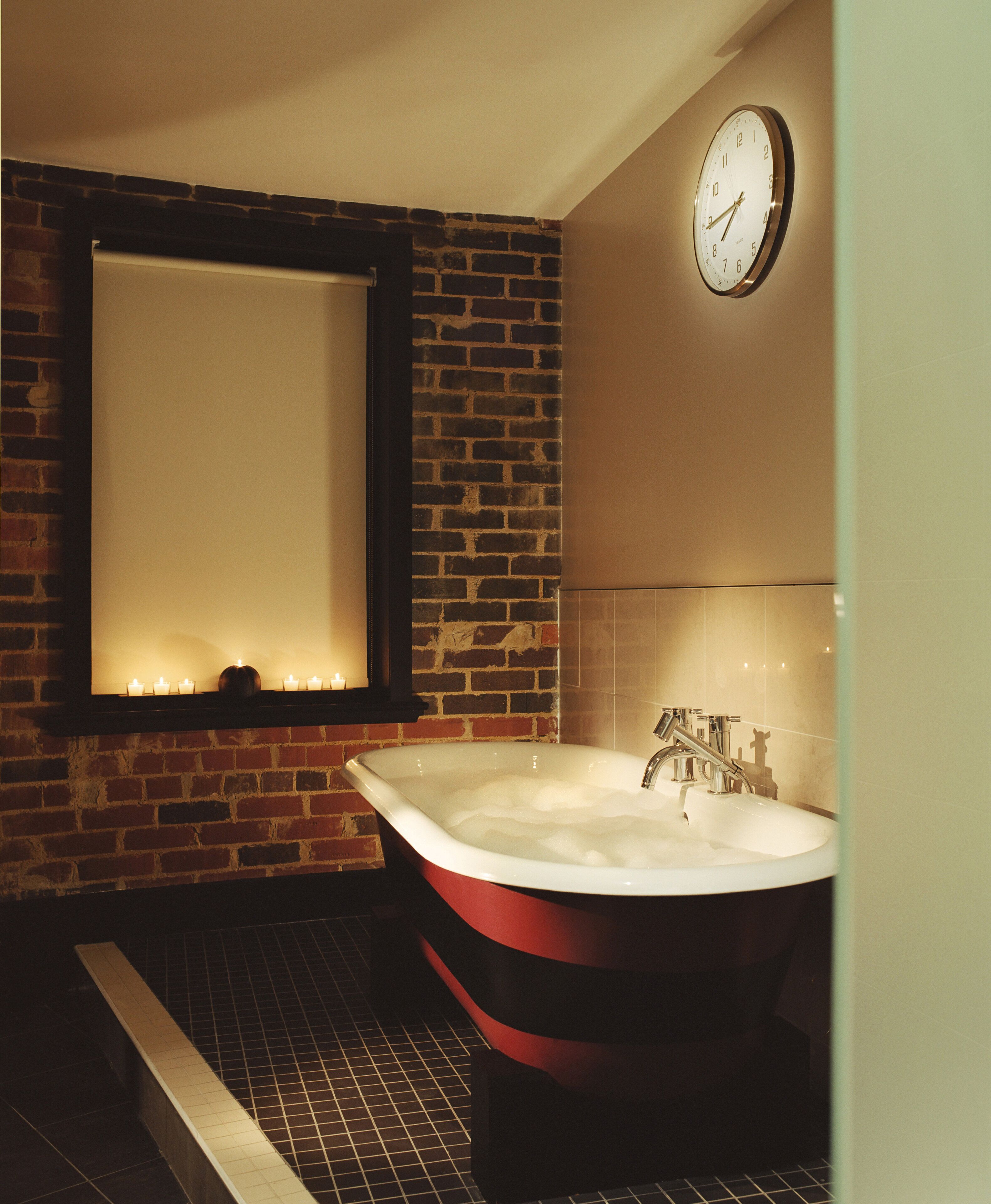 A bathroom with a large bathtub, a mirror, and a clock on the wall.