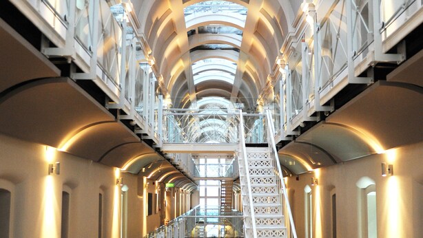 A multi-level interior with a central staircase, glass railings, and a high ceiling with skylights. - Malmaison Oxford (Oxford)