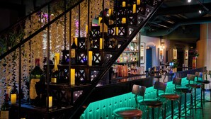 A bar area with a staircase, bar stools, and bottles. - Malmaison Oxford (Oxford)