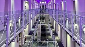 A multi-level hotel interior with a central staircase, glass railings, and purple lighting. - Malmaison Oxford (Oxford)
