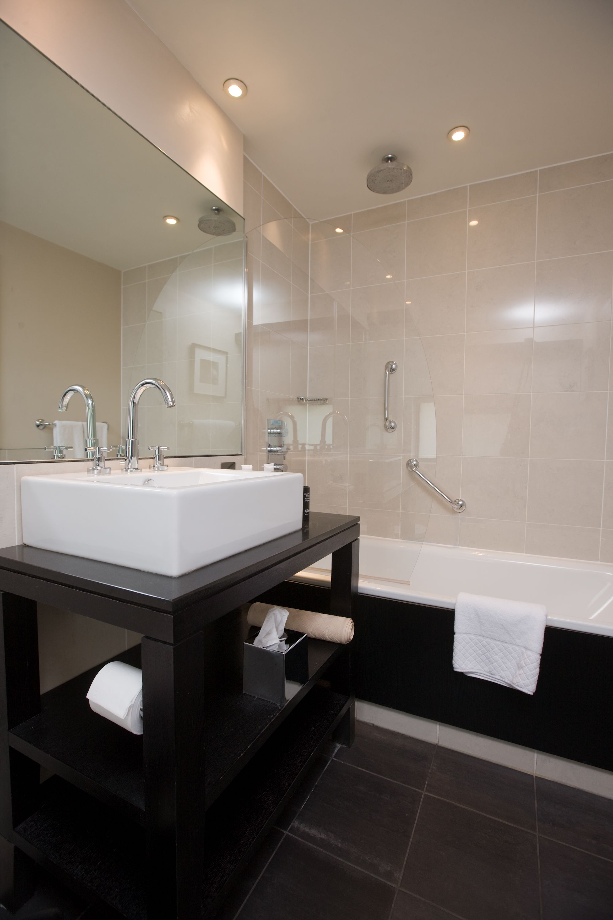 A modern bathroom with a large sink, mirror, and bathtub.