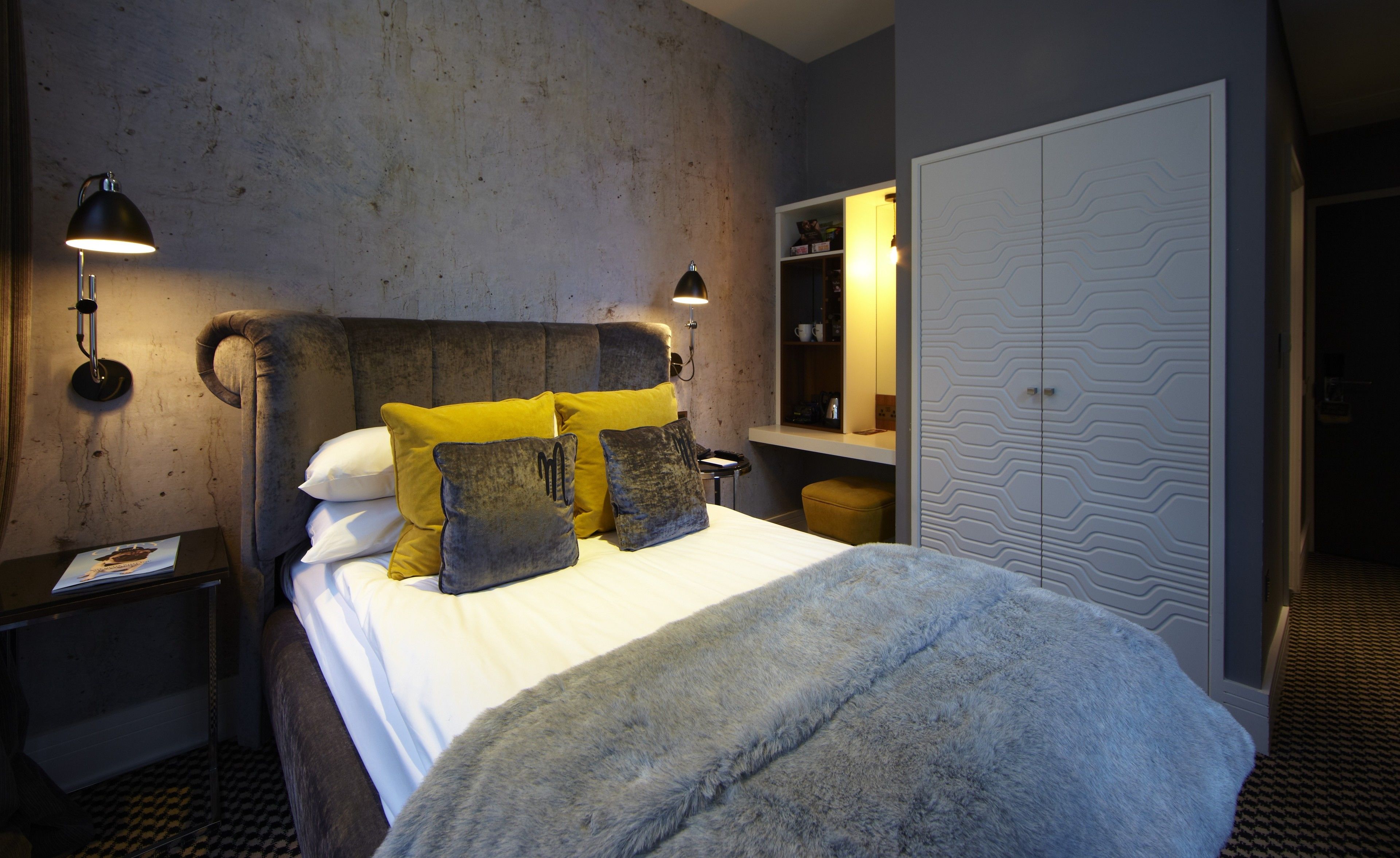 Un dormitorio con cama, dos lámparas de noche, una mesita de noche, un armario y un espejo.