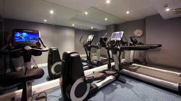 Ein Fitnessraum mit Cardiogeräten, Laufband und Spiegelwand.