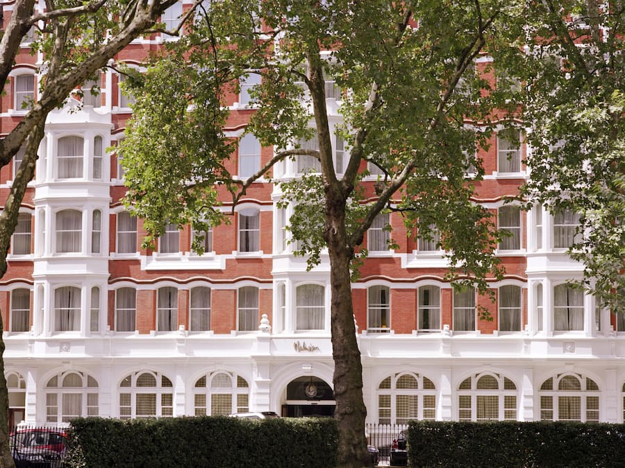 A large, historic building with multiple windows and a prominent tree in front.