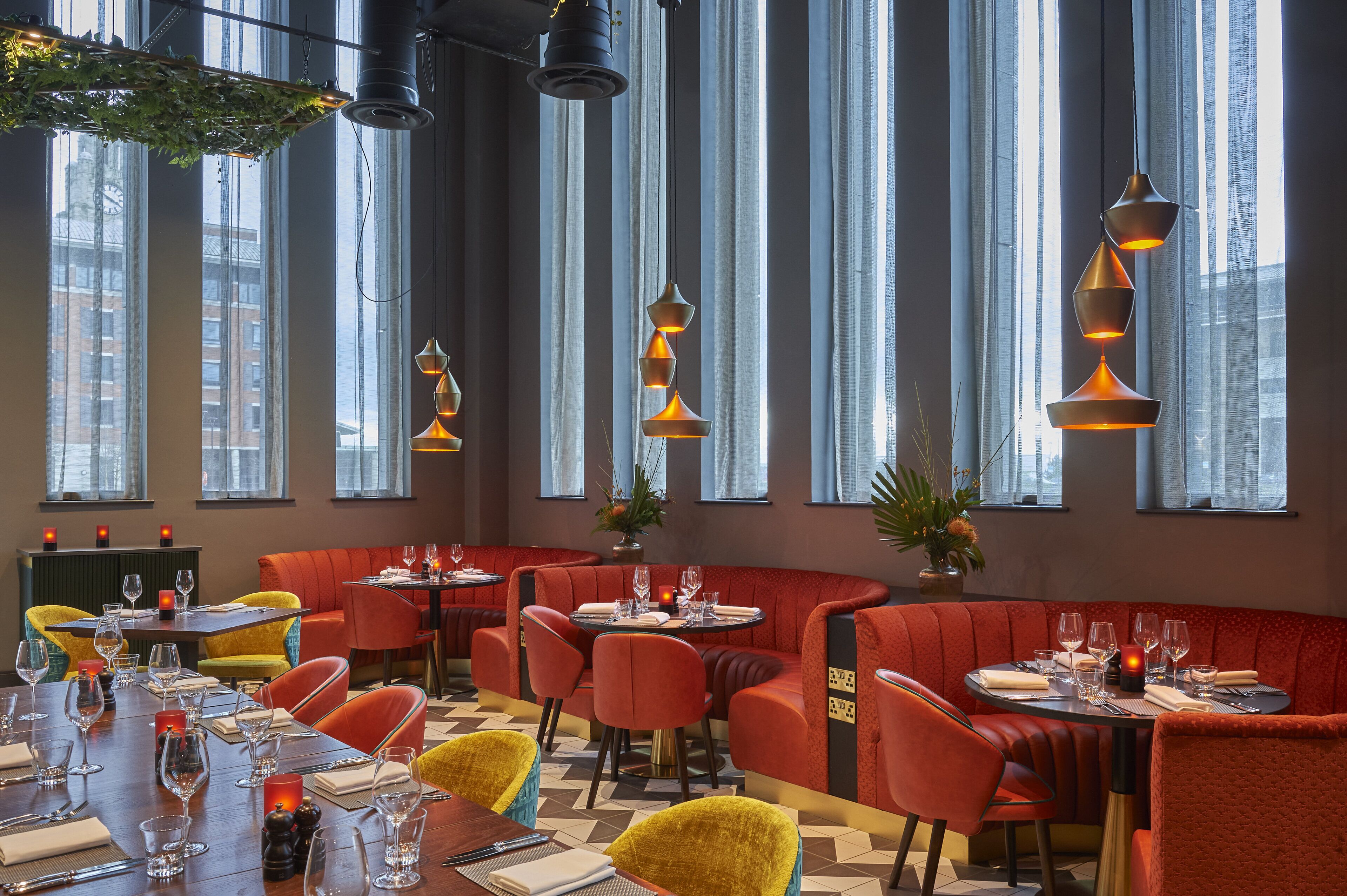 A restaurant with red booths, yellow chairs, and a wooden table set for dining.