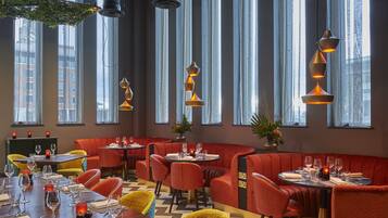 A restaurant with red booths, yellow chairs, and a wooden table set for dining.