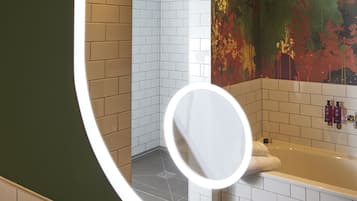 A bathroom with a bathtub, a shower area, and a green wall.