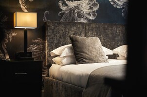 A bedroom with a large bed, a nightstand with a lamp, and a decorative wall mural.