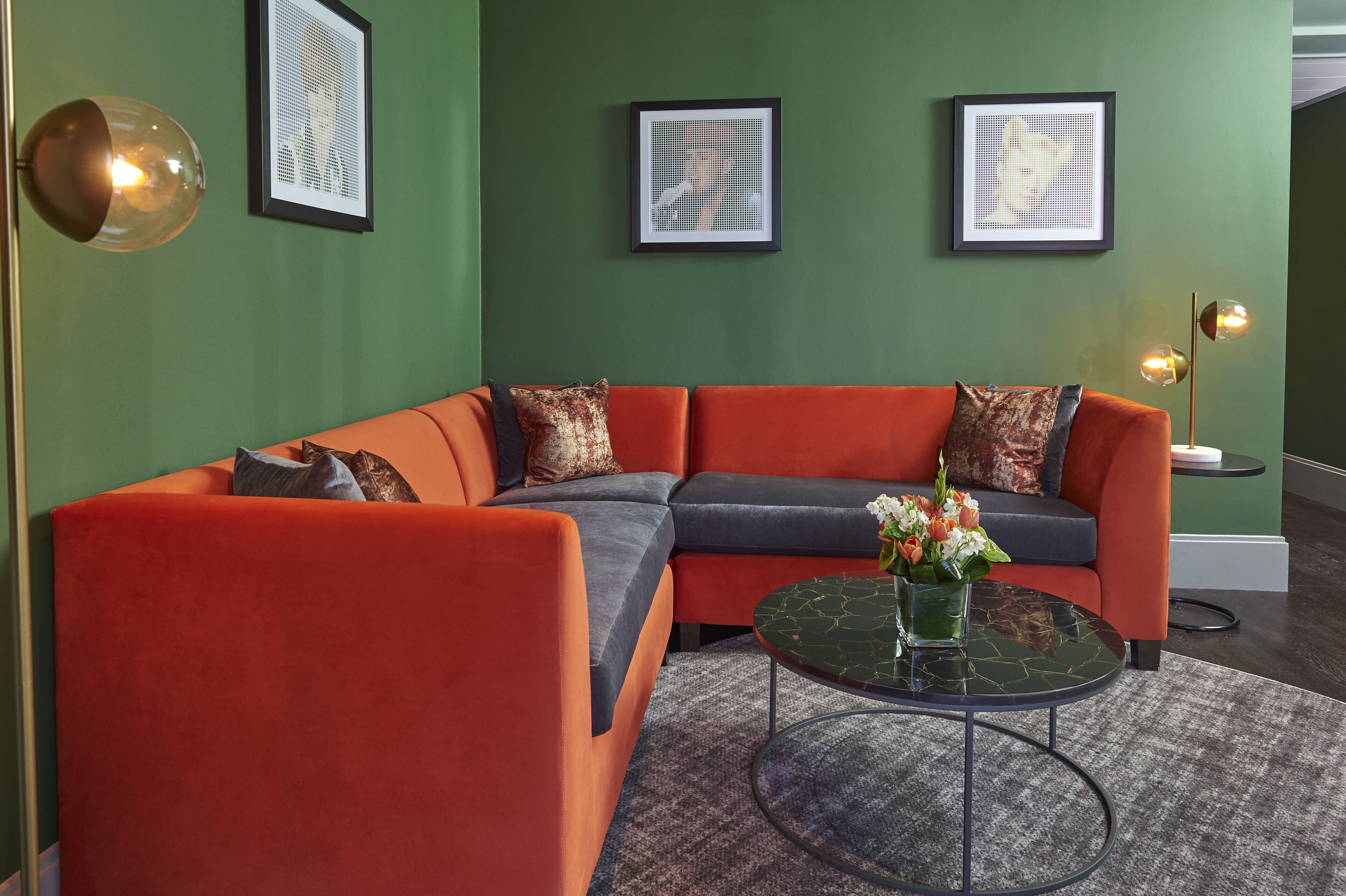 A modern living room with a sectional sofa, a round coffee table, and framed artwork on the walls.