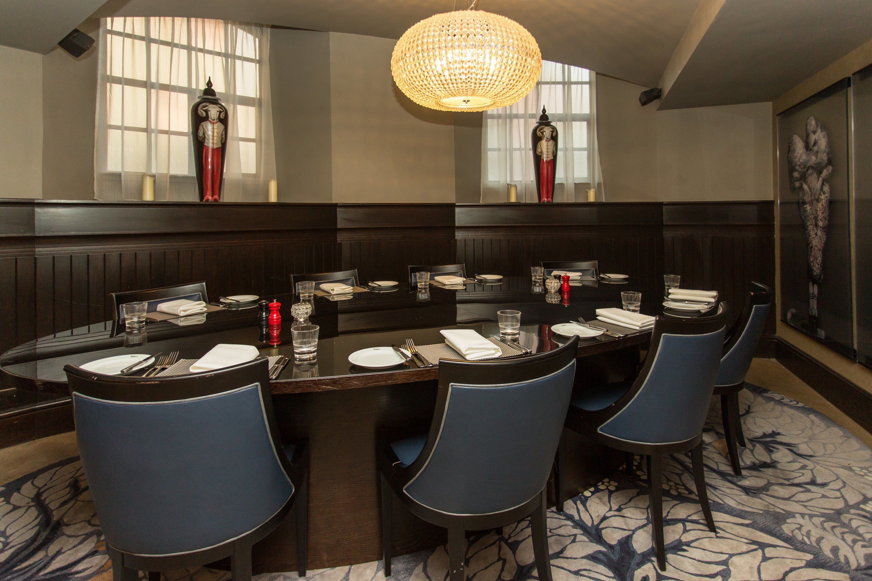 A dining area with a large rectangular table set for multiple guests, surrounded by blue chairs.