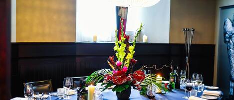 A dining table set for a meal with a centerpiece of flowers, candles, and wine glasses.