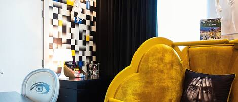 A room with a yellow sofa, a patterned wall, and a blue carpet with text.