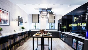 Una cocina moderna con una encimera larga, taburetes de bar y un refrigerador con un rótulo que dice 'WORK+PLAY'.