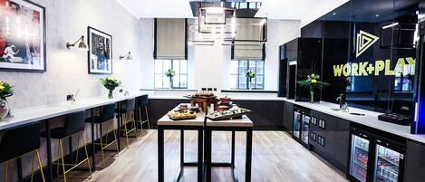 Una cocina moderna con una encimera larga, taburetes de bar y un refrigerador con un rótulo que dice 'WORK+PLAY'.