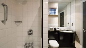 Ein modernes Badezimmer mit einer gläsernen Duschkabine, einer Toilette und einem Waschbecken mit schwarzer Arbeitsplatte.