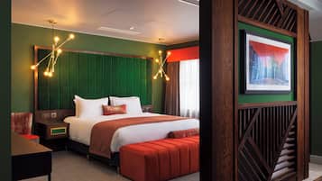A hotel room with a large bed, a wooden headboard, a red bench, a nightstand, and a framed picture on the wall.