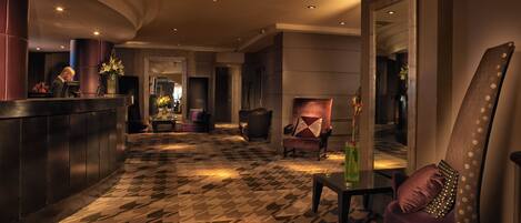 A lobby with a patterned floor, a reception desk, seating area, and a mirror.