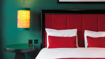 Una habitación de hotel con cabecera roja, una mesa redonda y una lámpara de pared.