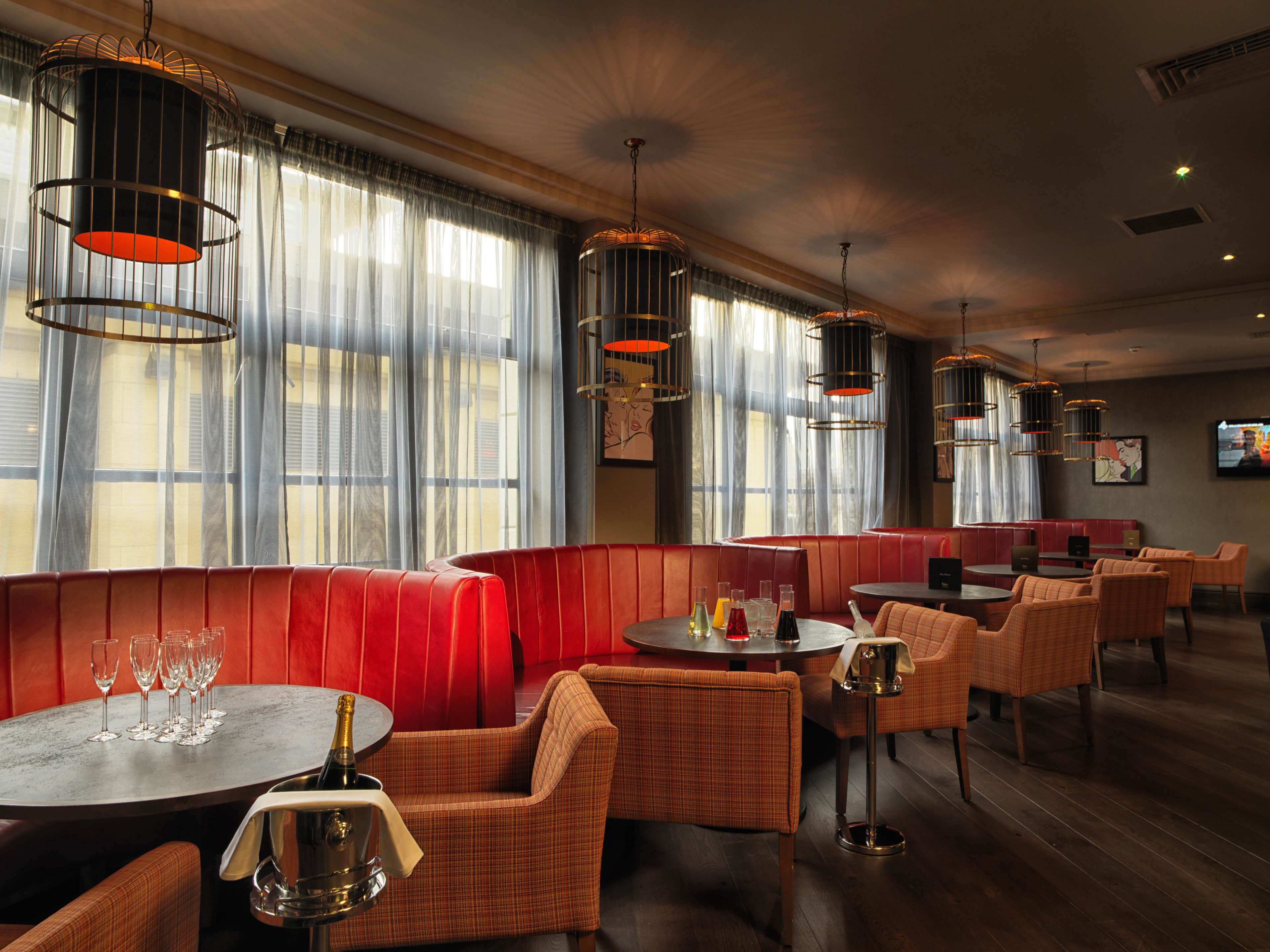 A restaurant with red booths, round tables, and wicker chairs.