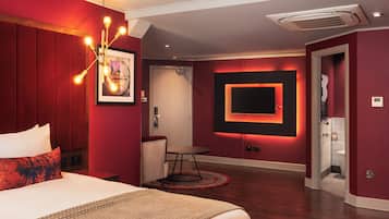 Habitación de hotel con una cama grande, un escritorio, una silla, un televisor montado en la pared y una puerta que da al baño.