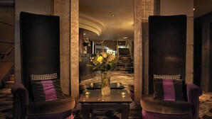 A lobby with a modern design, featuring a central seating area with two sofas and a coffee table, flanked by tall columns. - Malmaison Newcastle (Newcastle-upon-Tyne)