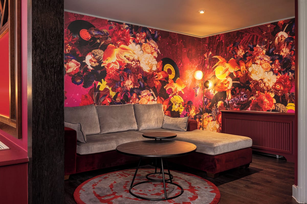 A modern living room with a sectional sofa, a round coffee table, and a vibrant floral mural on the wall.