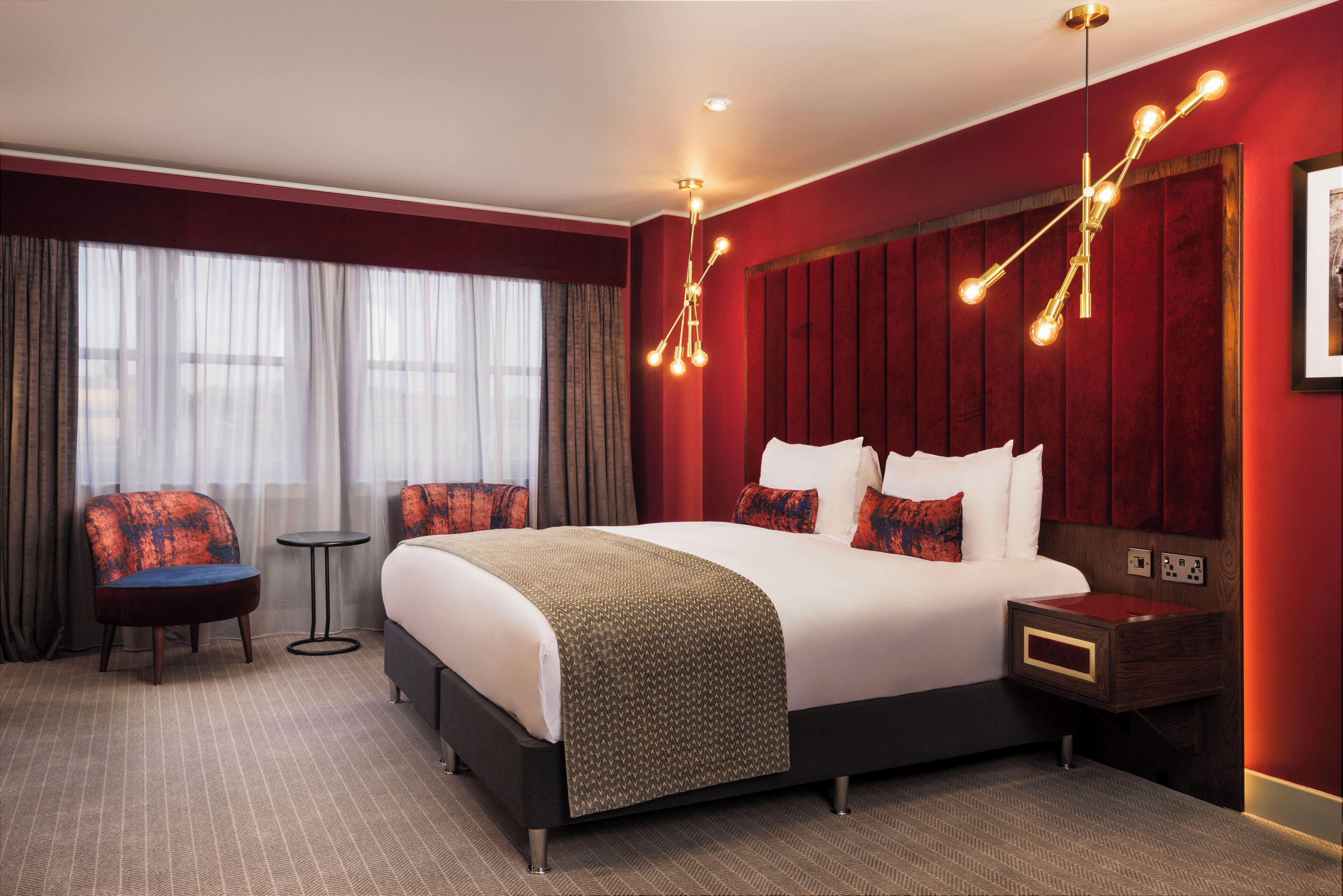 Une chambre d’hôtel avec un grand lit, deux chaises, une petite table et une table de chevet.