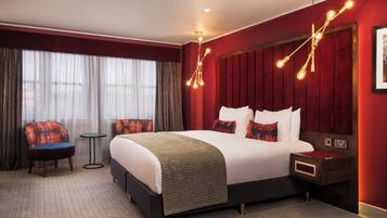 Une chambre d’hôtel avec un grand lit, deux chaises, une petite table et une table de chevet.