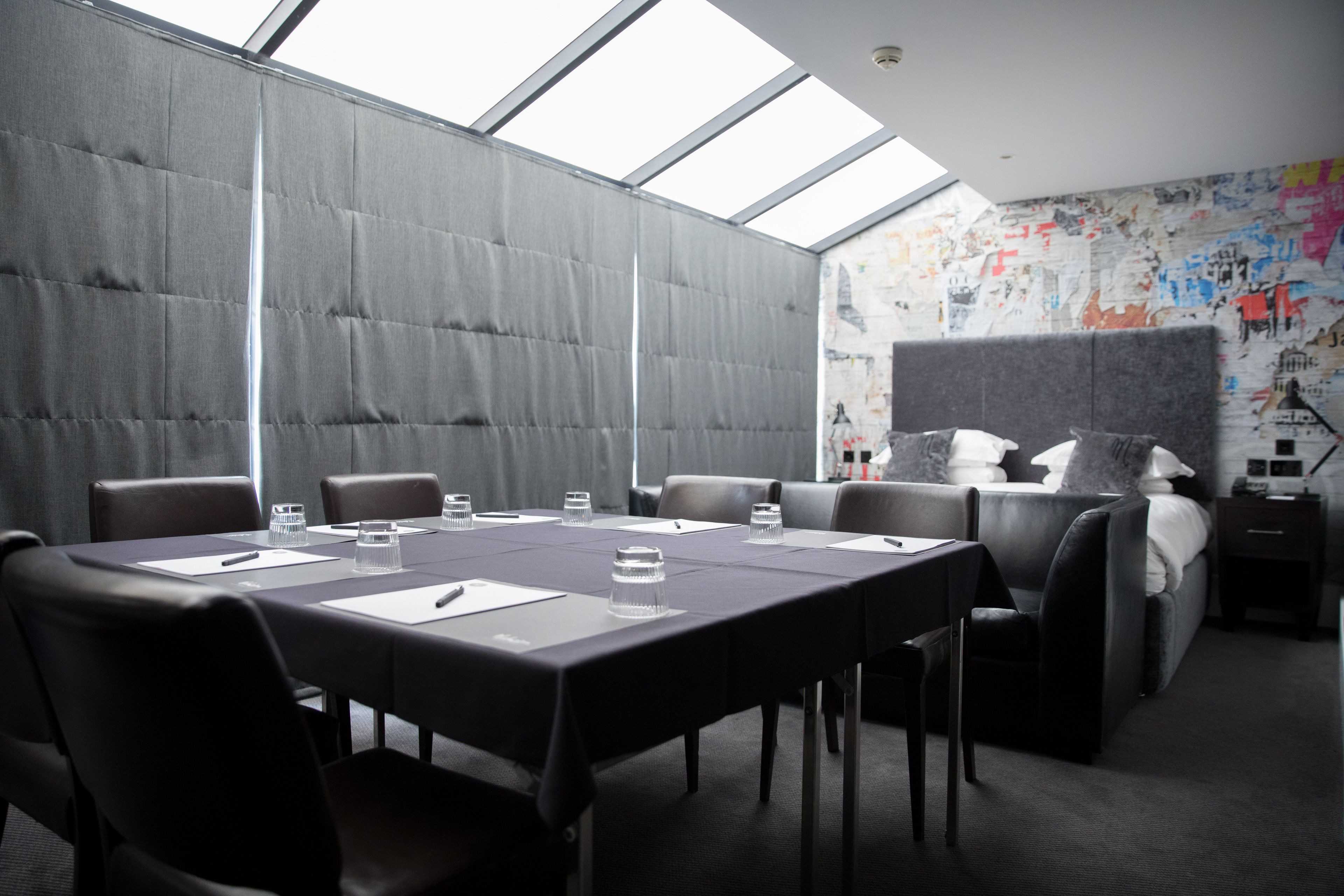 Une salle de conférence dotée d’un plafond haut, d’une grande table et de plusieurs chaises.