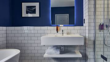Une salle de bain moderne avec un lavabo blanc, une douche en verre et un mur d’accent bleu.