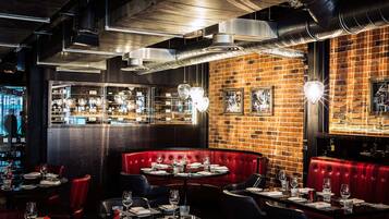 A restaurant with a brick wall, red booths, and a bar area.