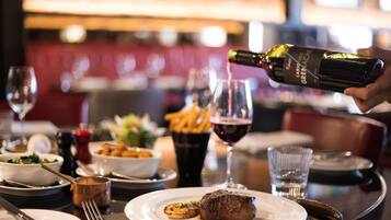 A dining table with plates, cutlery, a bottle of wine, and glasses.