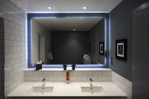 A modern bathroom with two sinks, a large mirror, and recessed lighting.
