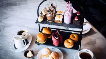 Un chariot de desserts avec divers pâtisseries, une tasse de café et un petit bol de crème fouettée.