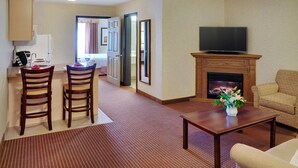 Una sala de estar con chimenea, televisor, sofá y una zona de comedor con sillas y mesa.