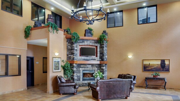 Un amplio hall de entrada con chimenea de piedra, sofás de cuero y una araña.