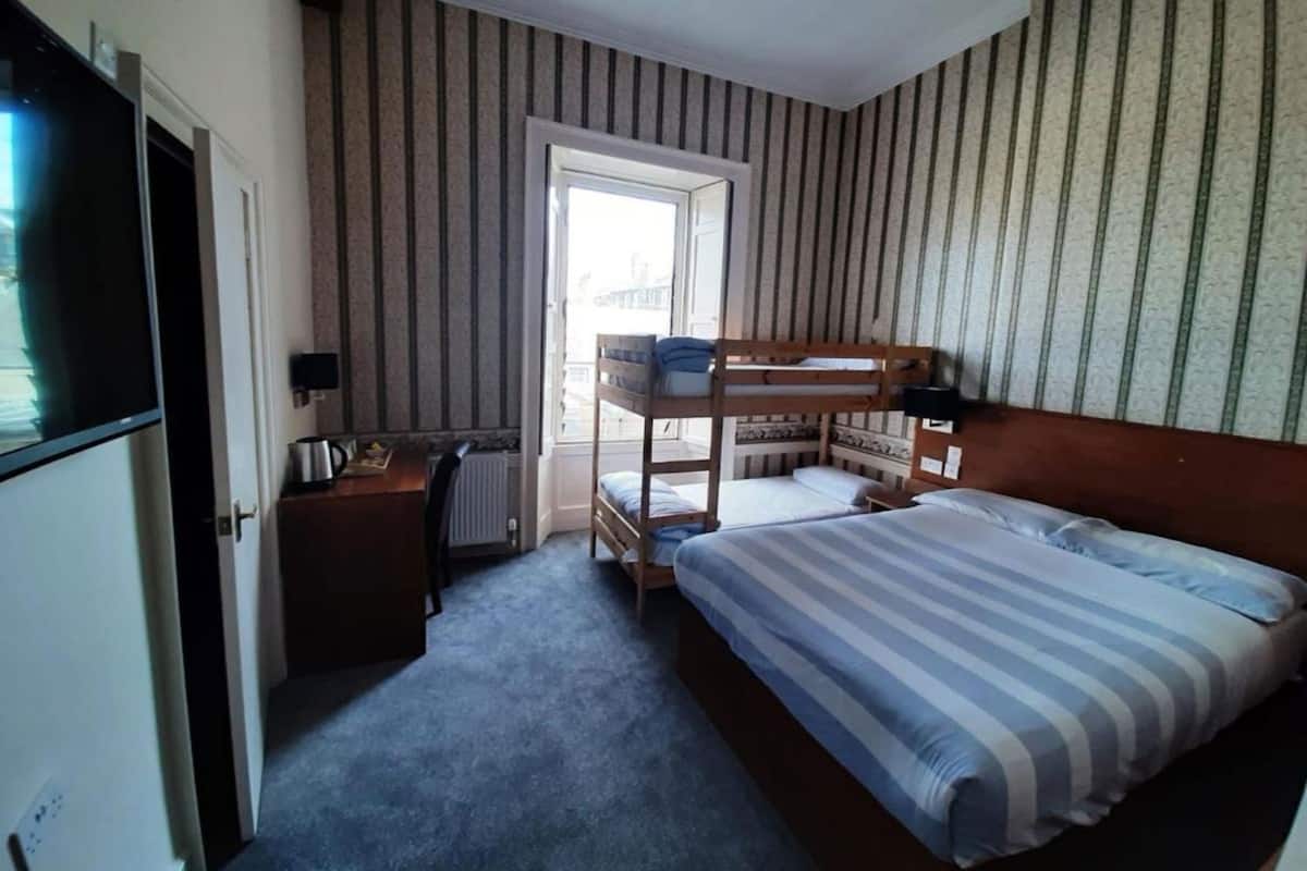 Une chambre avec un lit superposé, un bureau, un radiateur et un téléviseur.