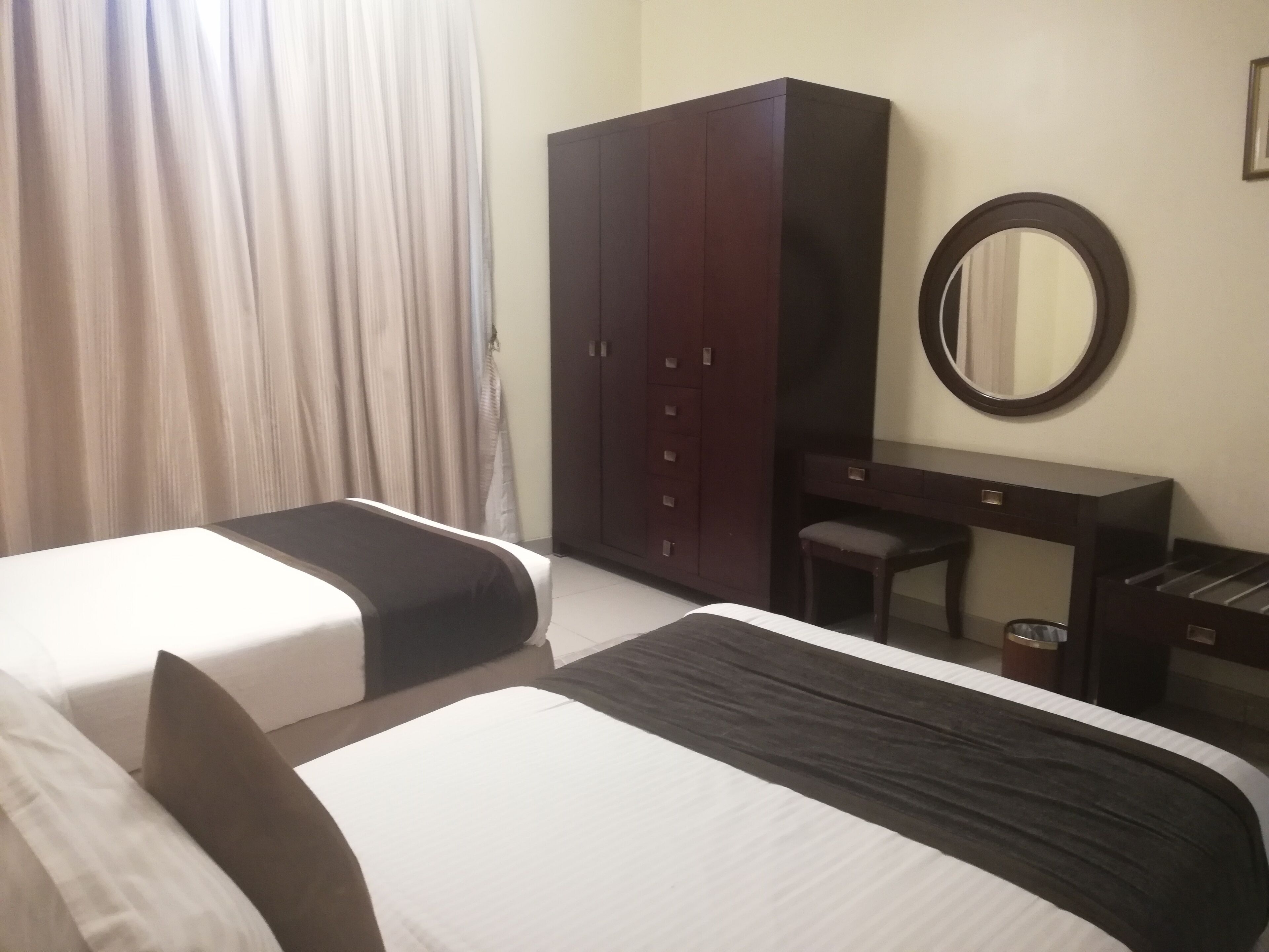 Une chambre d’hôtel avec deux lits, une armoire, un bureau et un miroir.