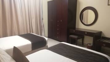 Une chambre d’hôtel avec deux lits, une armoire, un bureau et un miroir.