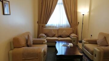 A living room with a sofa set, two armchairs, a coffee table, and a floor lamp.