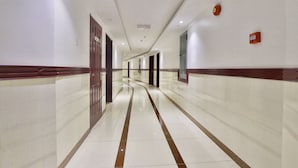 A long, well-lit hallway with a shiny tiled floor and wooden trim. - Crown Palace Hotel Ajman (Ajman)