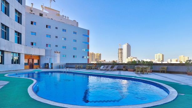 A rooftop swimming pool with lounge chairs and a view of the city skyline. - Crown Palace Hotel Ajman (Ajman)