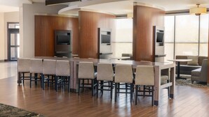 A modern dining area with a long table and chairs, a flat-screen TV, and a large window providing natural light. - Residence Inn Youngstown Warren/Niles (Niles)